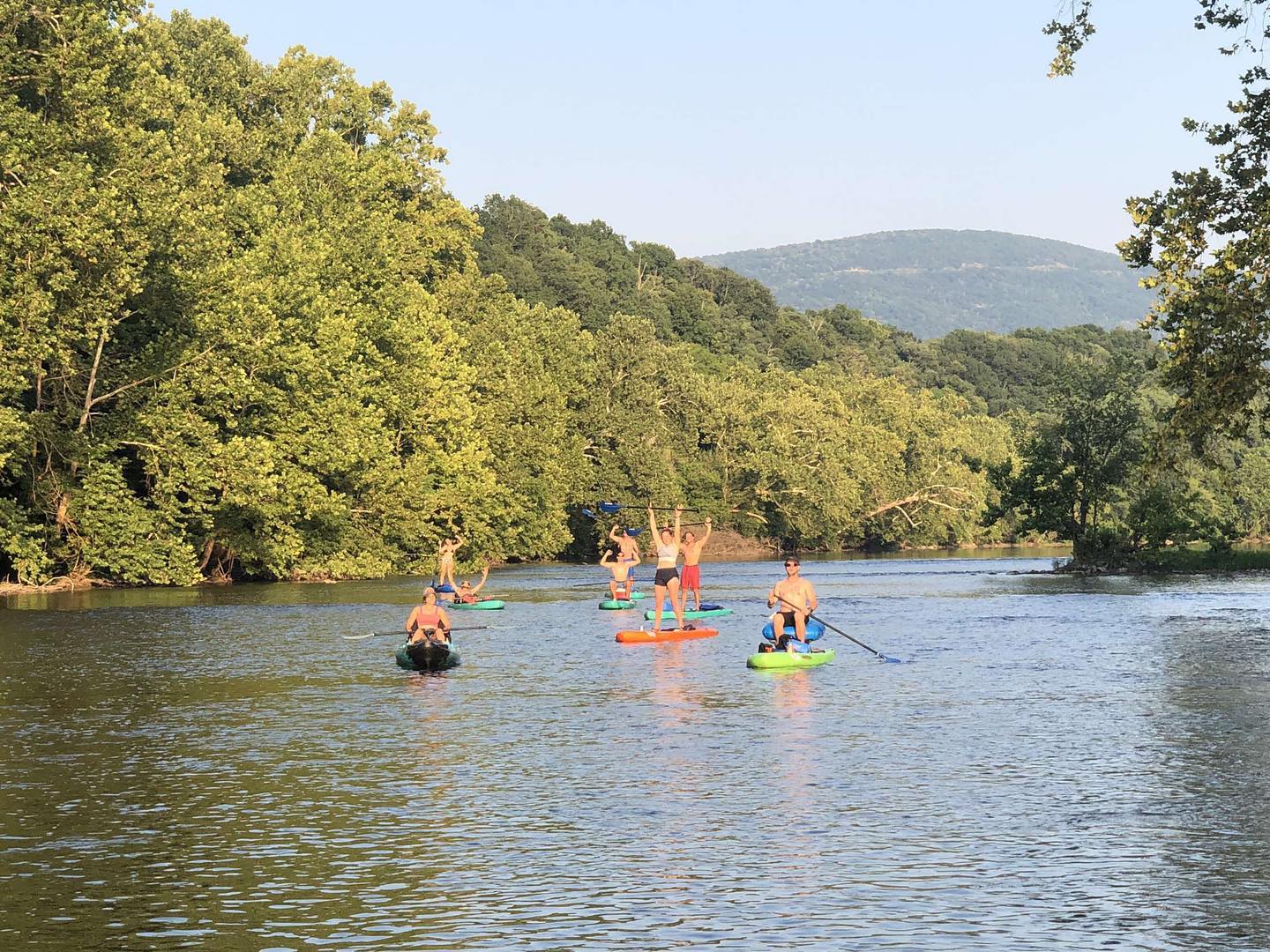 a group of people on SUPs and canoes float down the Shenandoah river