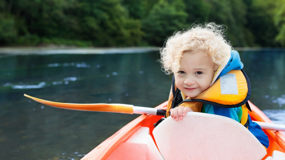 Child in life vest with a paddle in hand