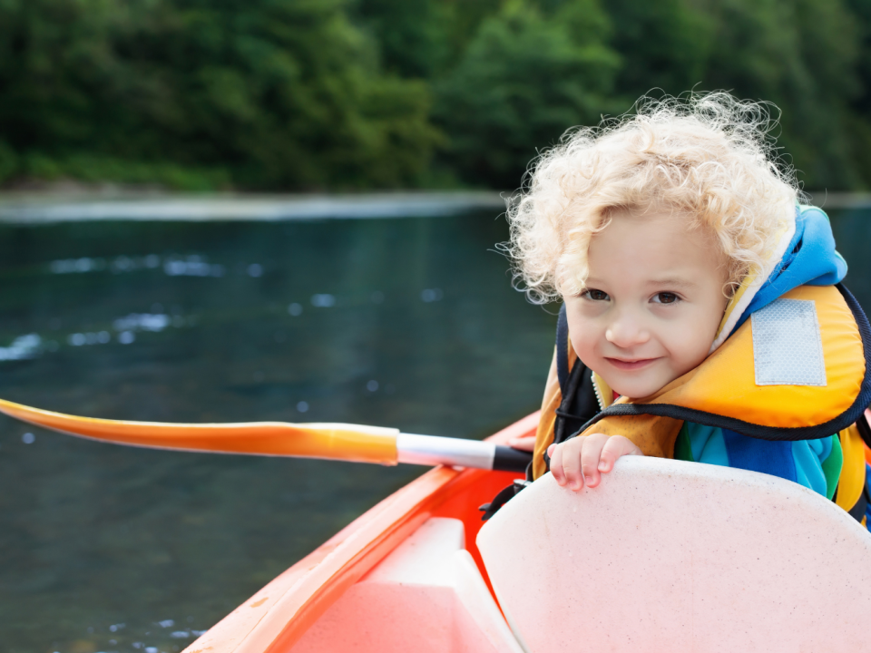Child in life vest with a paddle in hand