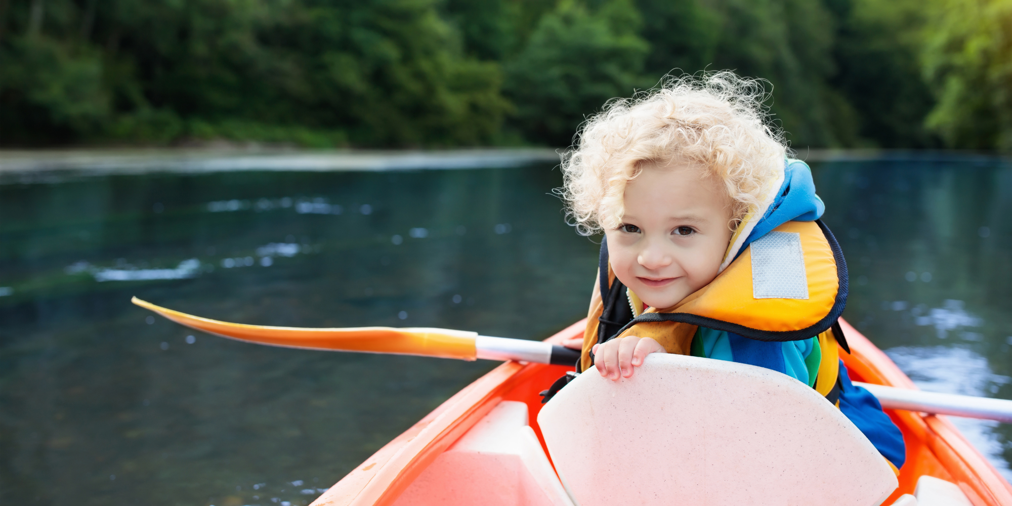 Child in life vest with a paddle in hand