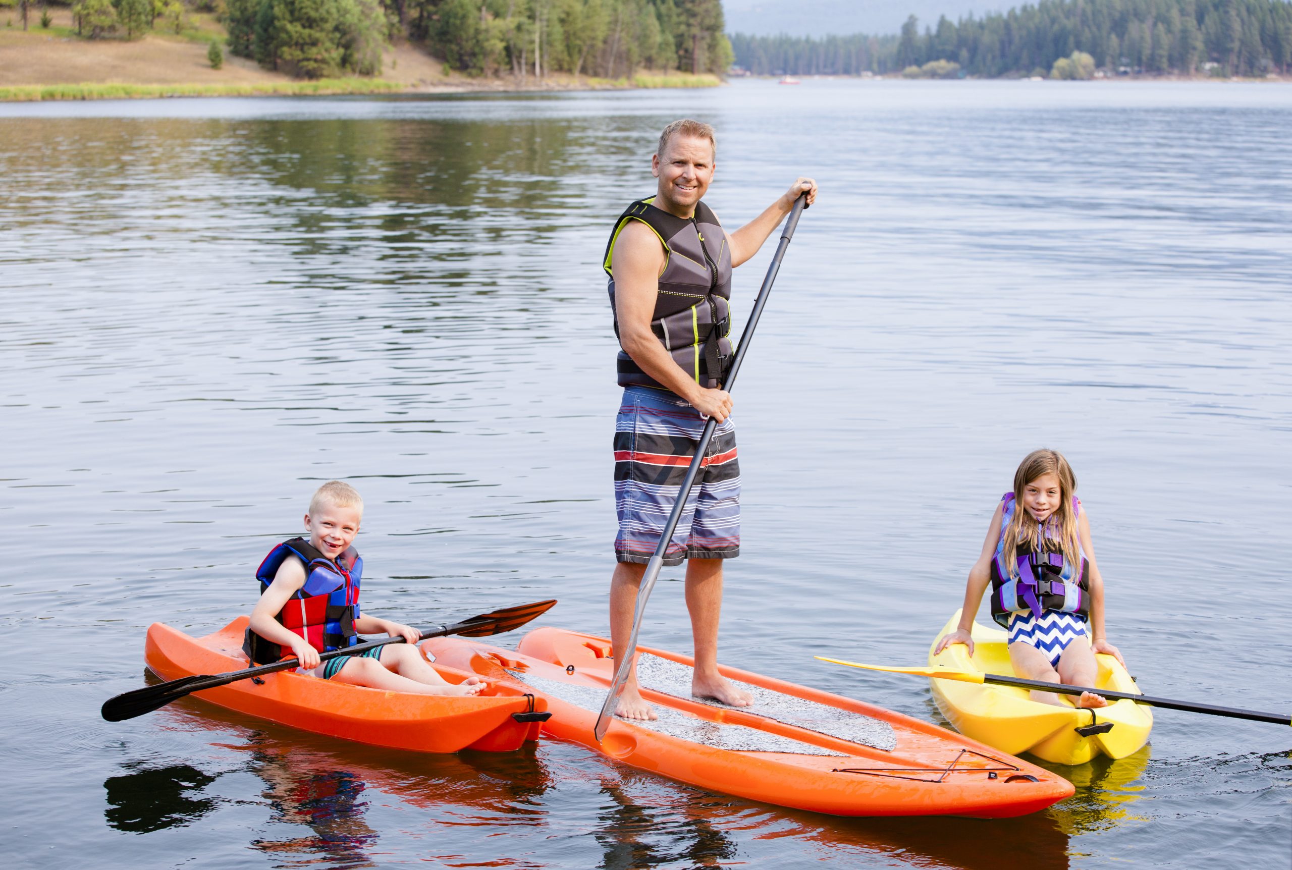 a family of three kayaking and paddle boarding