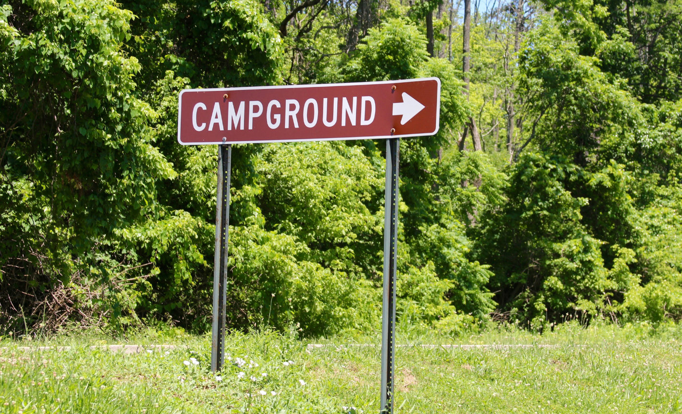 a sign stands in a green field and reads "CAMPGROUND" with a right arrow