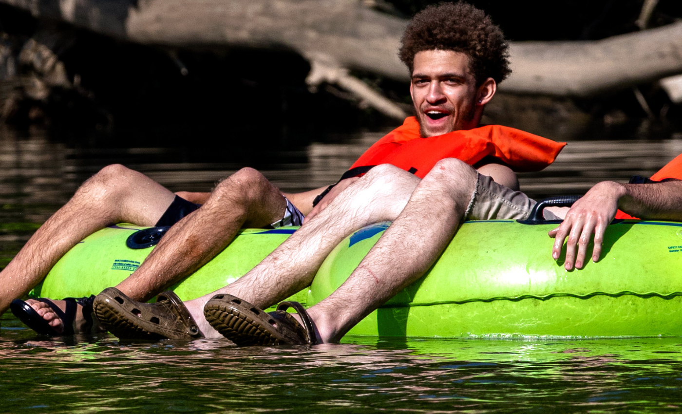 man sits in green tube while he floats a river