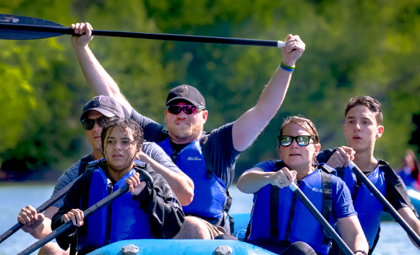 a family paddles in a blue raft on the river