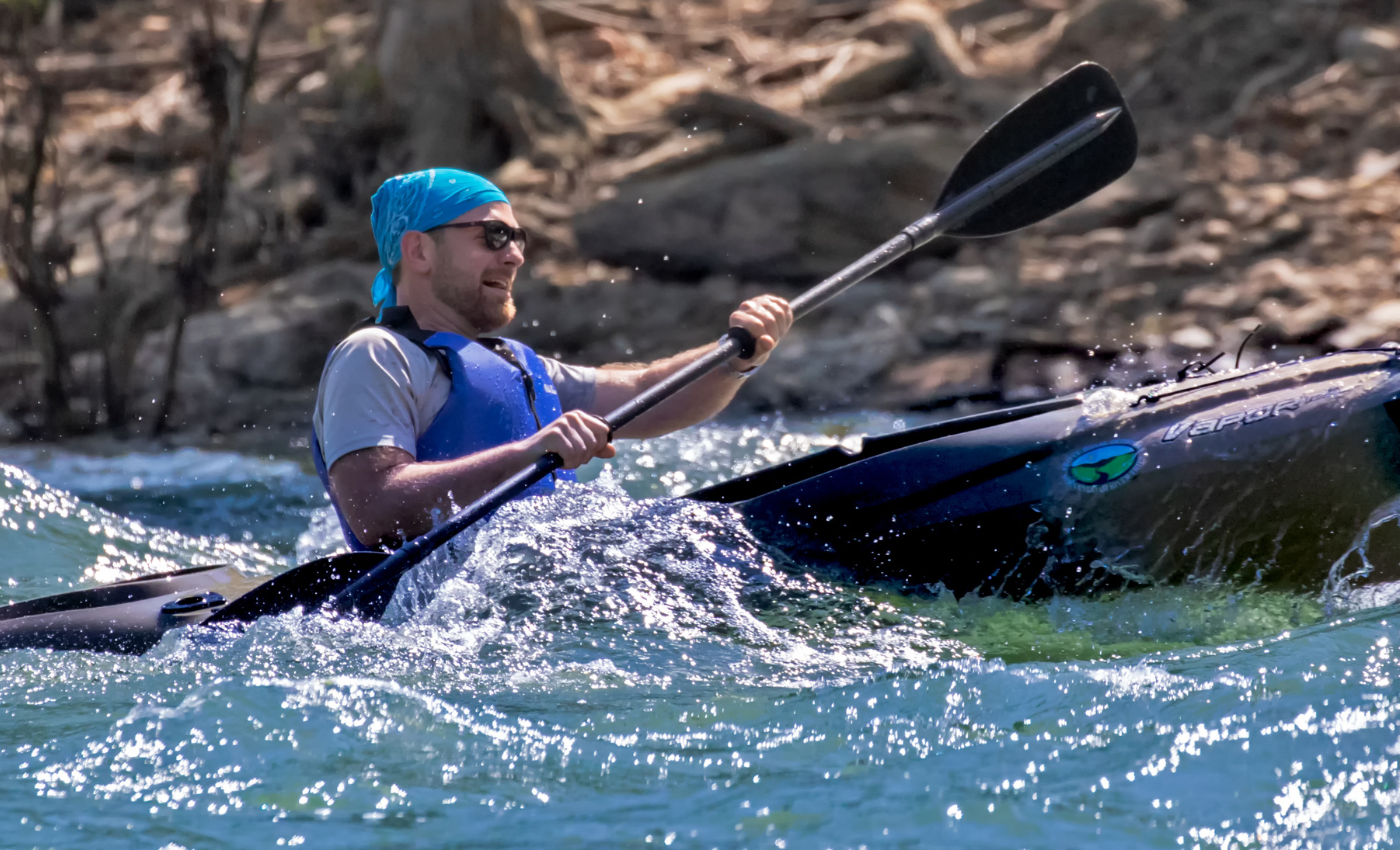 man in kayak paddles on a river