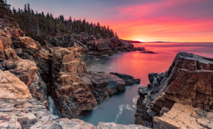 acadia national park coastline with a vibrant pink sunset on the water