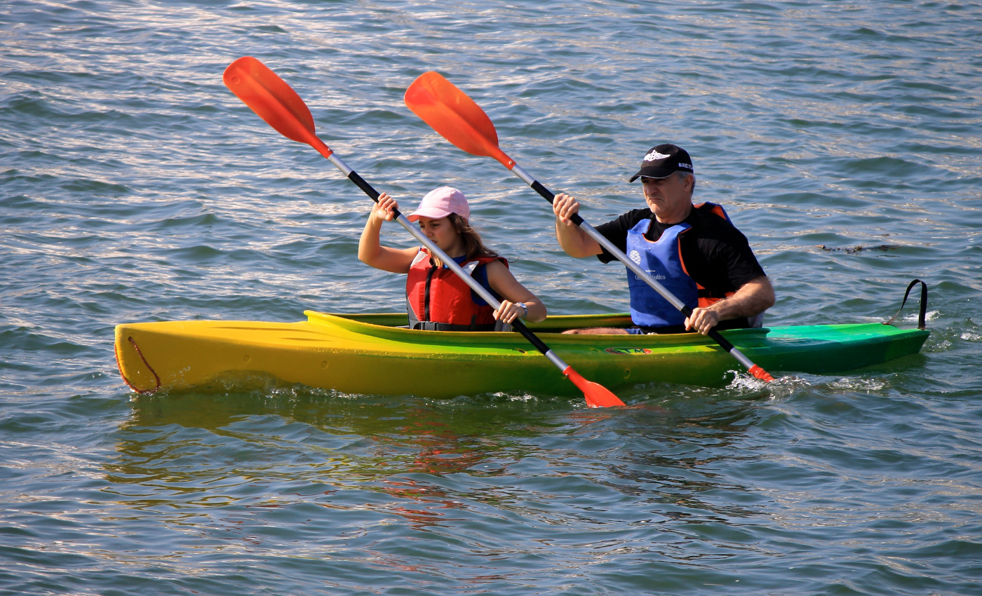 two canoers paddle with red paddles on choppy water