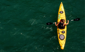 a woman in a yellow kayak paddles on a river