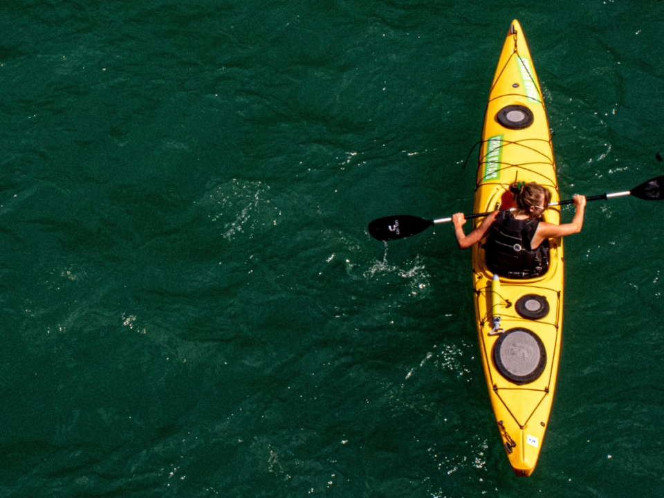 a woman in a yellow kayak paddles on a river