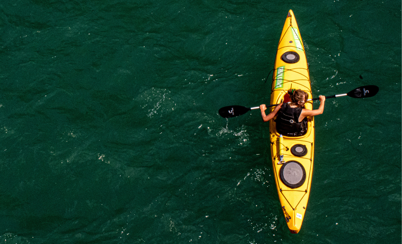 a woman in a yellow kayak paddles on a river