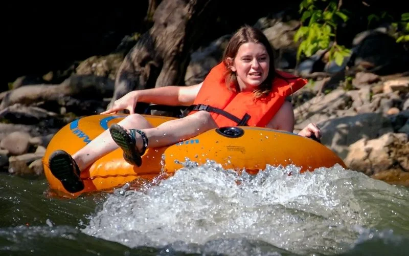 a girl floats down river in an orange tube