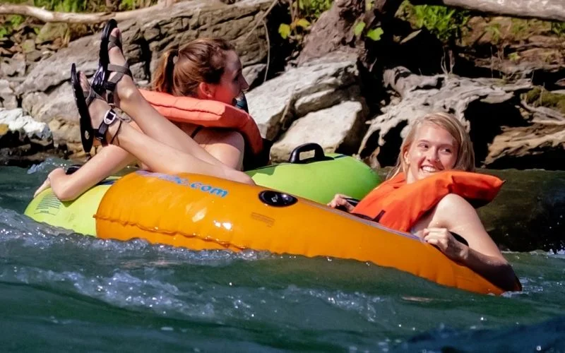 A woman sits in an orange river tube